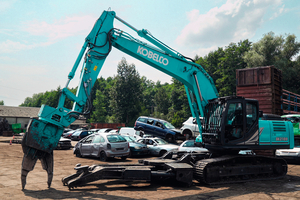  Der Demontage-Bagger Kobelco SK210D mit Schrottschere und Multifunktions-Klemmzange am Unterwagen 